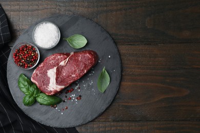 Photo of Fresh raw cut beef, spices and basil leaves on wooden table, top view. Space for text