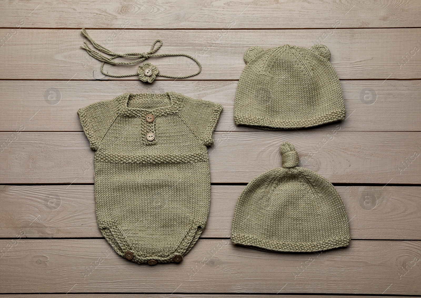 Photo of Set of cute baby knitwear for photoshoot on wooden background, flat lay