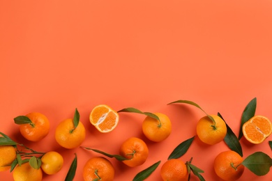 Fresh tangerines with green leaves on coral background, flat lay. Space for text
