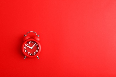 Modern alarm clock on red background, top view. Space for text