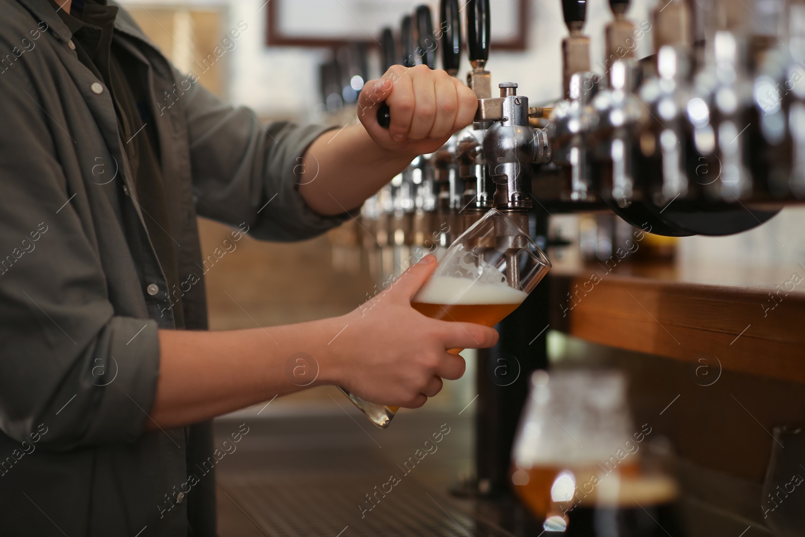 Photo of Bartender pouring fresh beer into glass in pub, closeup