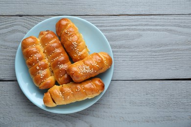 Photo of Delicious sausage rolls on grey wooden table, top view. Space for text