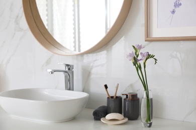 Photo of Beautiful violet freesia flowers on countertop in bathroom