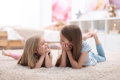 Photo of Cute little sisters on floor at home
