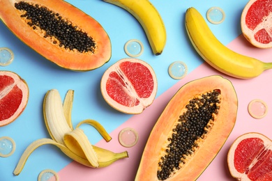 Photo of Flat lay composition with condoms and exotic fruits on color background. Erotic concept