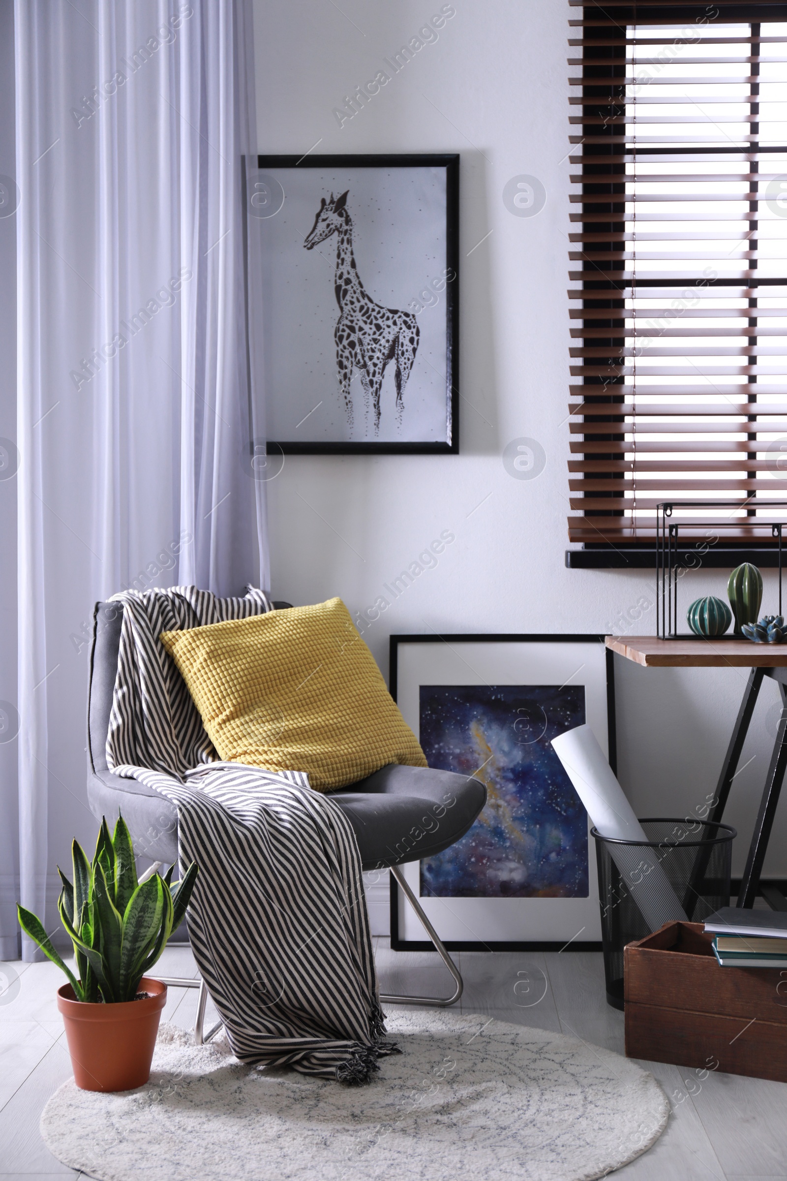 Photo of Comfortable armchair and table near window with horizontal blinds