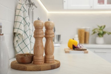 Photo of Wooden salt and pepper shakers, bowl with bay leaves on white countertop, space for text