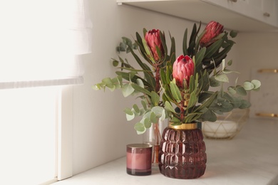 Photo of Beautiful protea flowers on countertop in kitchen. Interior design