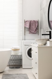 Photo of Stylish bathroom interior with heated towel rail and modern washing machine