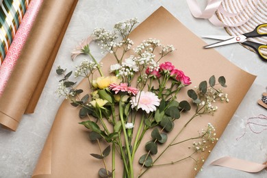 Photo of Beautiful flowers and wrapping papers on grey table, flat lay. Arranging bouquet