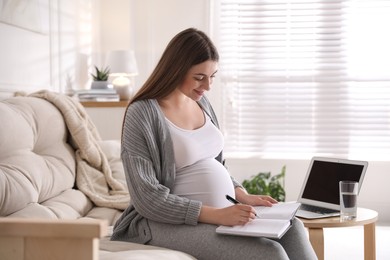 Pregnant woman working on sofa at home. Maternity leave