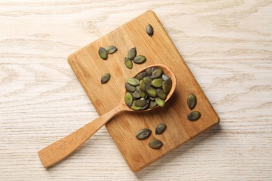 Photo of Spoon with pumpkin seeds on wooden table, top view