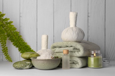 Photo of Composition with different spa products and candle on white table against wooden background. Space for text