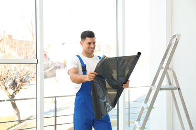 Professional worker with foil indoors. Window tinting