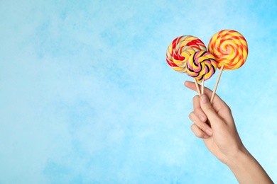 Woman holding yummy candies on color background. Space for text