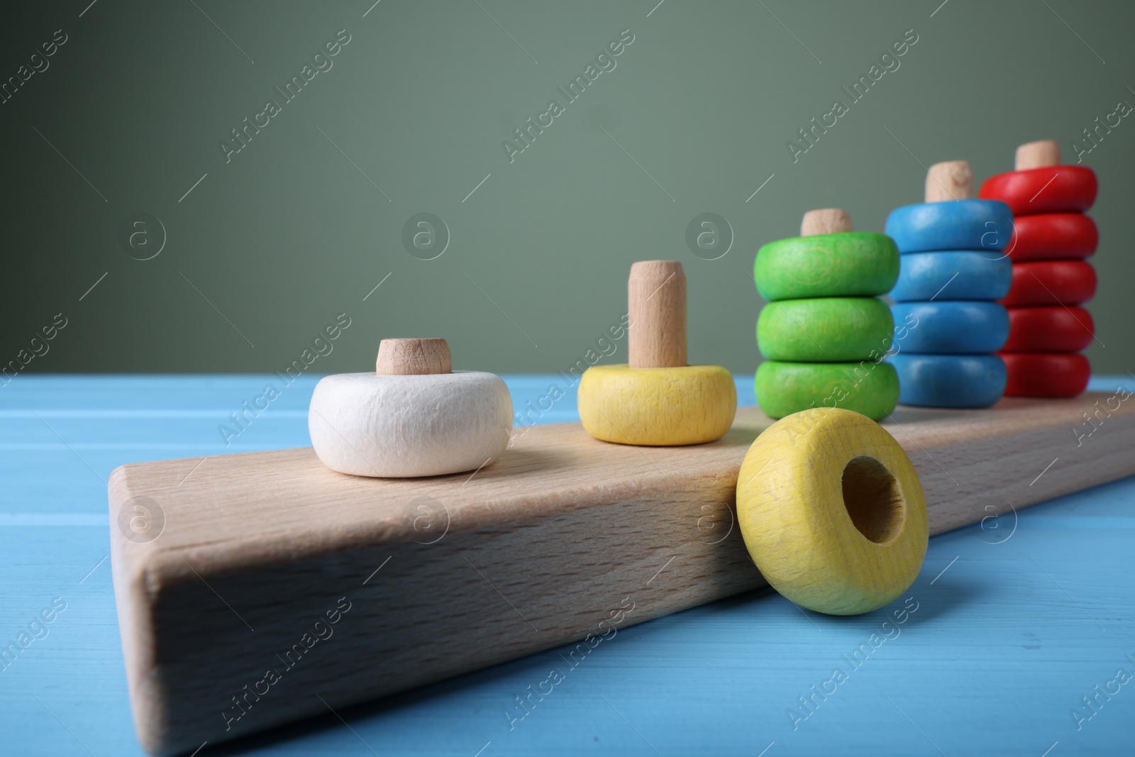 Photo of Stacking and counting game pieces on light blue table against grey wall, closeup. Motor skills development