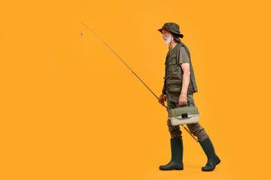 Photo of Fisherman with rod and box for fishing tackle on yellow background, space for text