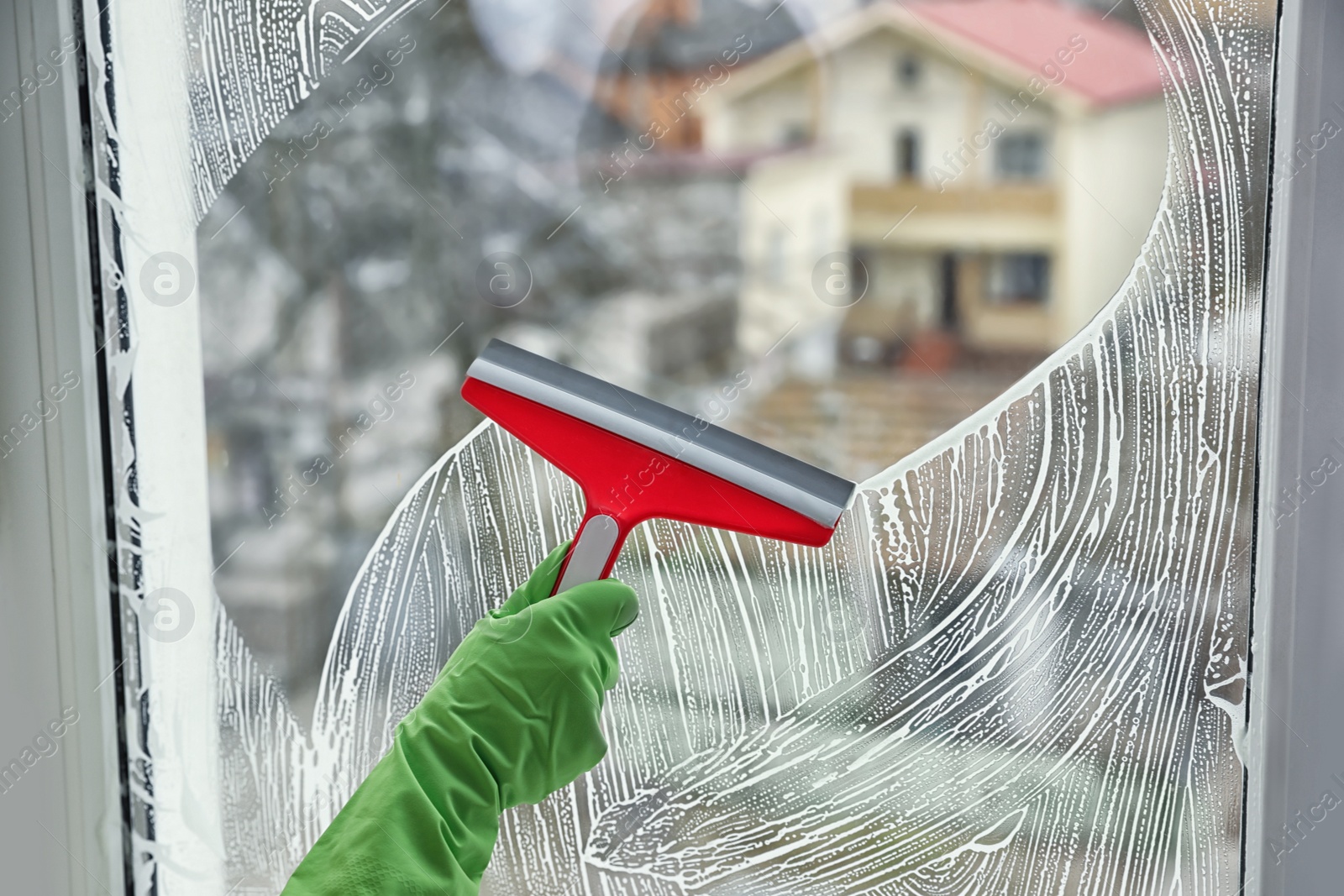 Photo of Woman cleaning window with squeegee indoors, closeup