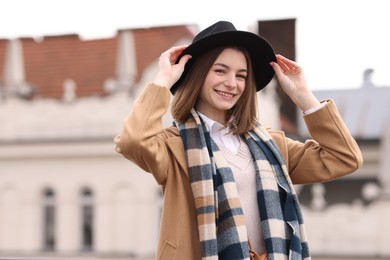 Photo of Beautiful woman in warm scarf and hat outdoors, space for text