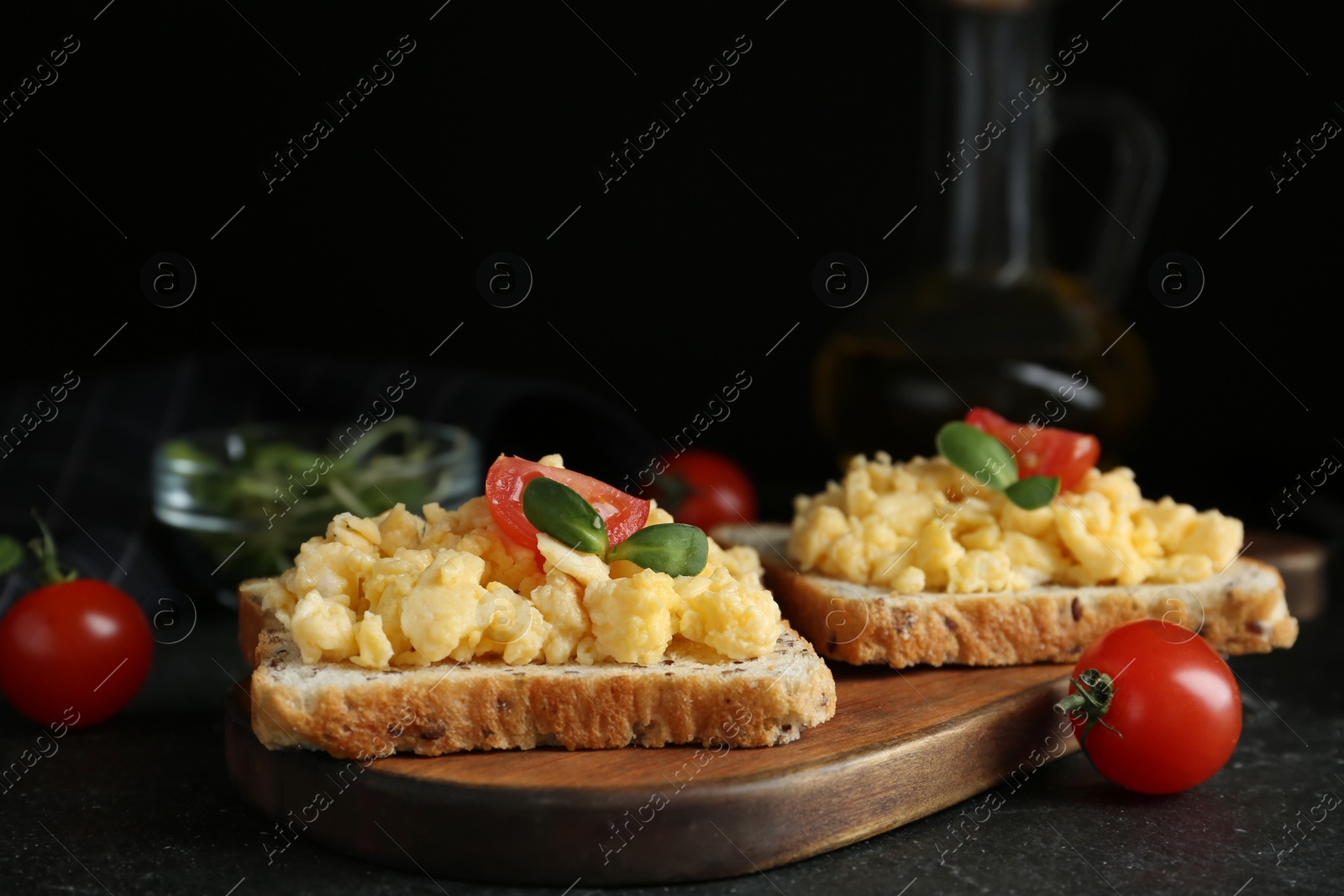 Photo of Tasty scrambled egg sandwiches served on wooden board