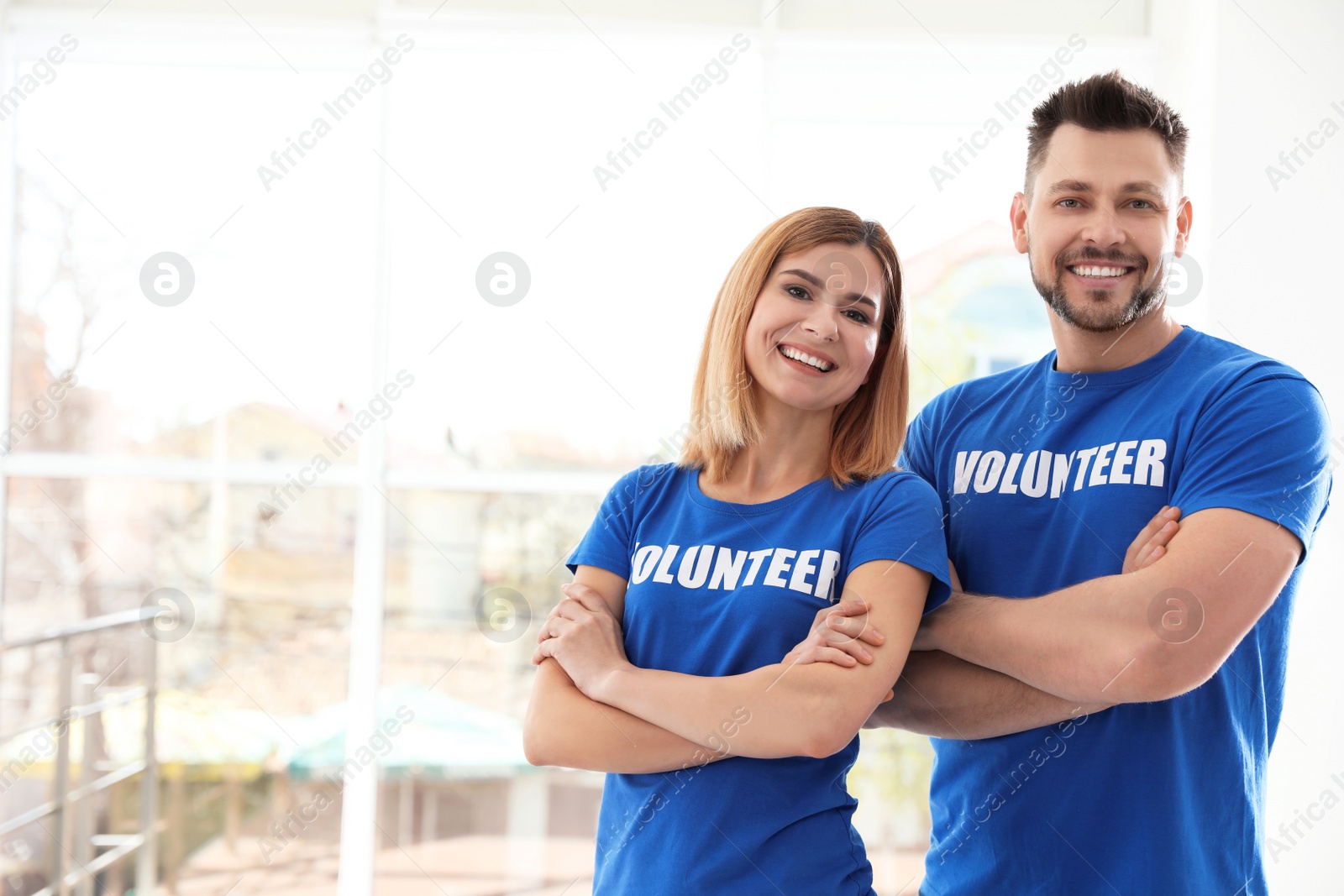 Photo of Portrait of happy volunteers in uniform indoors. Space for text