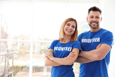 Portrait of happy volunteers in uniform indoors. Space for text