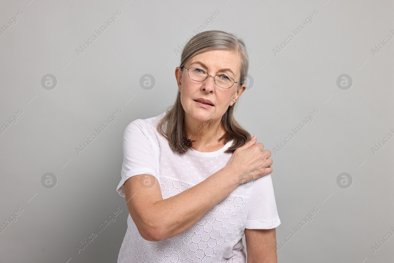 Photo of Arthritis symptoms. Woman suffering from pain in shoulder on gray background