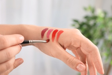 Photo of Woman testing and choosing lip gloss color on hand, closeup