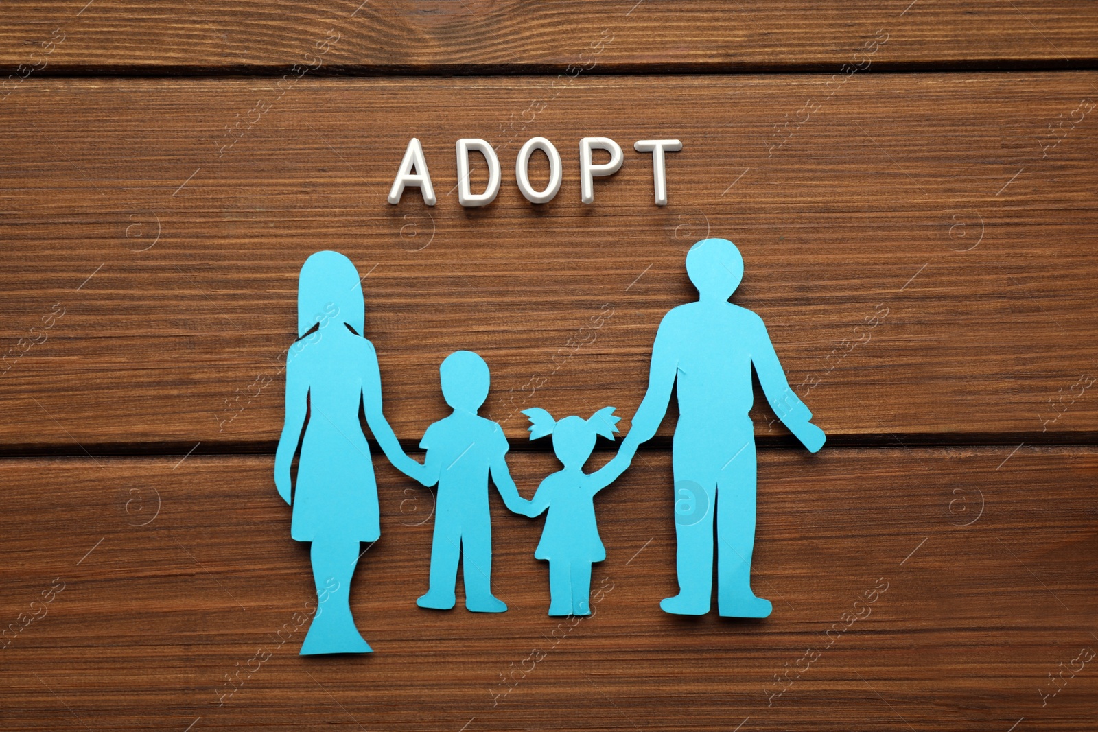 Photo of Family figure and word Adopt on wooden table, flat lay