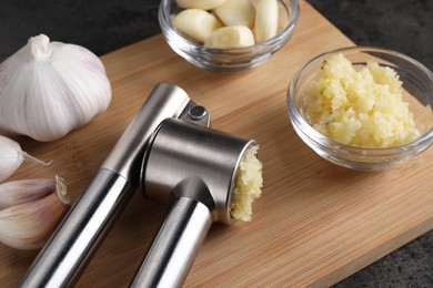 Photo of Garlic press, cloves and mince on wooden table, closeup