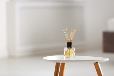 Photo of Aromatic reed air freshener on table against blurred background