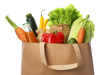 Paper bag with vegetables and bottle of juice on white background, closeup