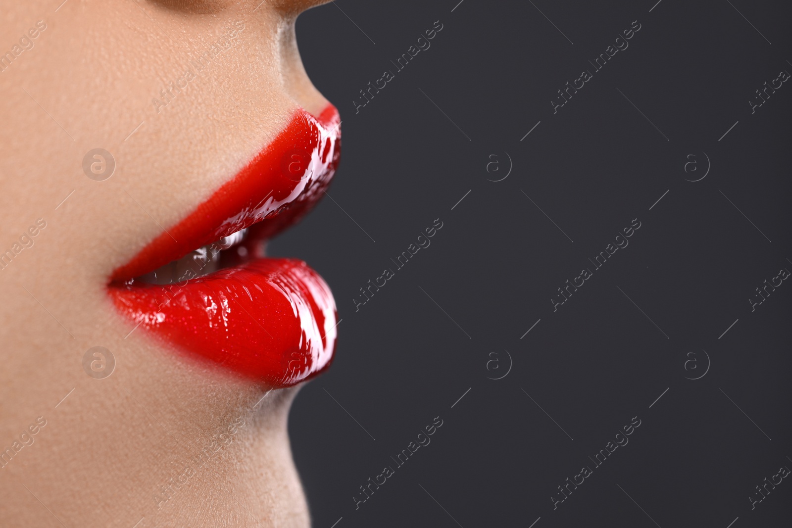 Photo of Young woman with beautiful red lips on grey background, closeup. Space for text