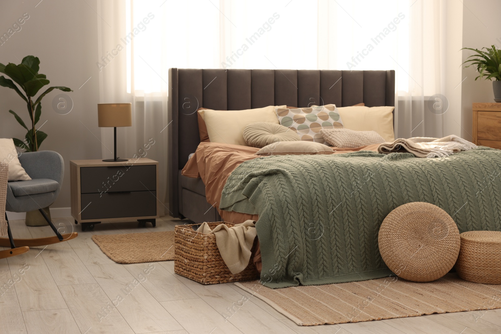 Photo of Large comfortable bed with soft pillows and blanket in room. Home textile