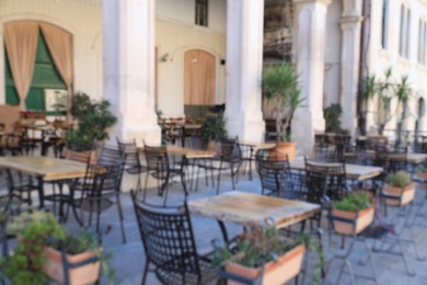 Photo of Outdoor cafe with stylish furniture and green plants, blurred view