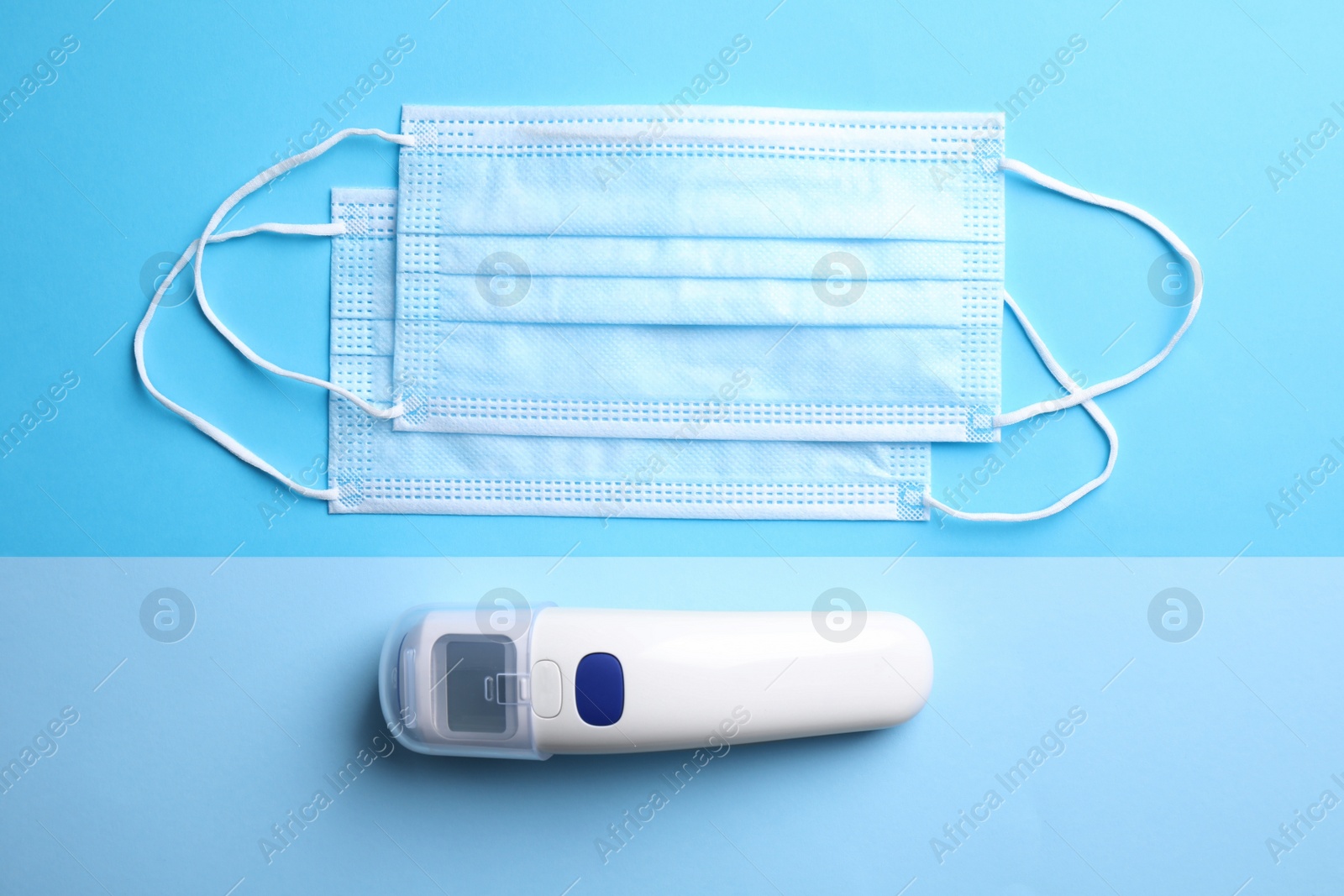 Photo of Non contact infrared thermometer and respiratory masks on color background, flat lay