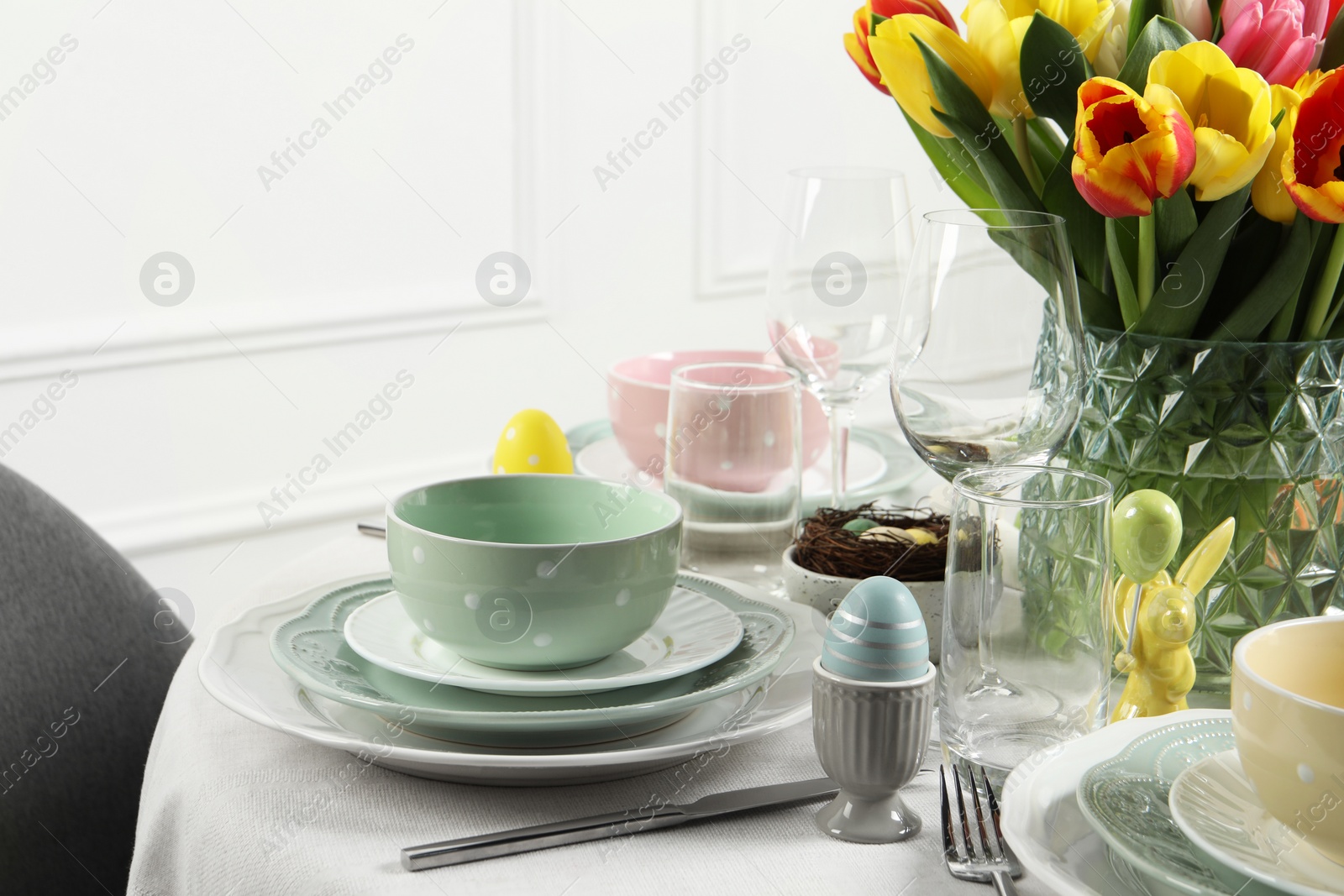 Photo of Easter celebration. Festive table setting with beautiful flowers and painted eggs