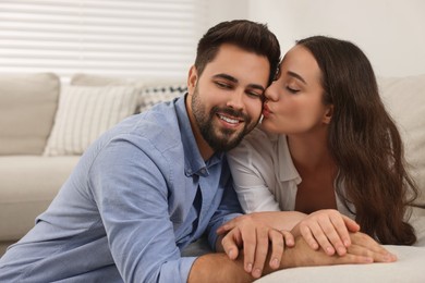 Young woman kissing her boyfriend at home