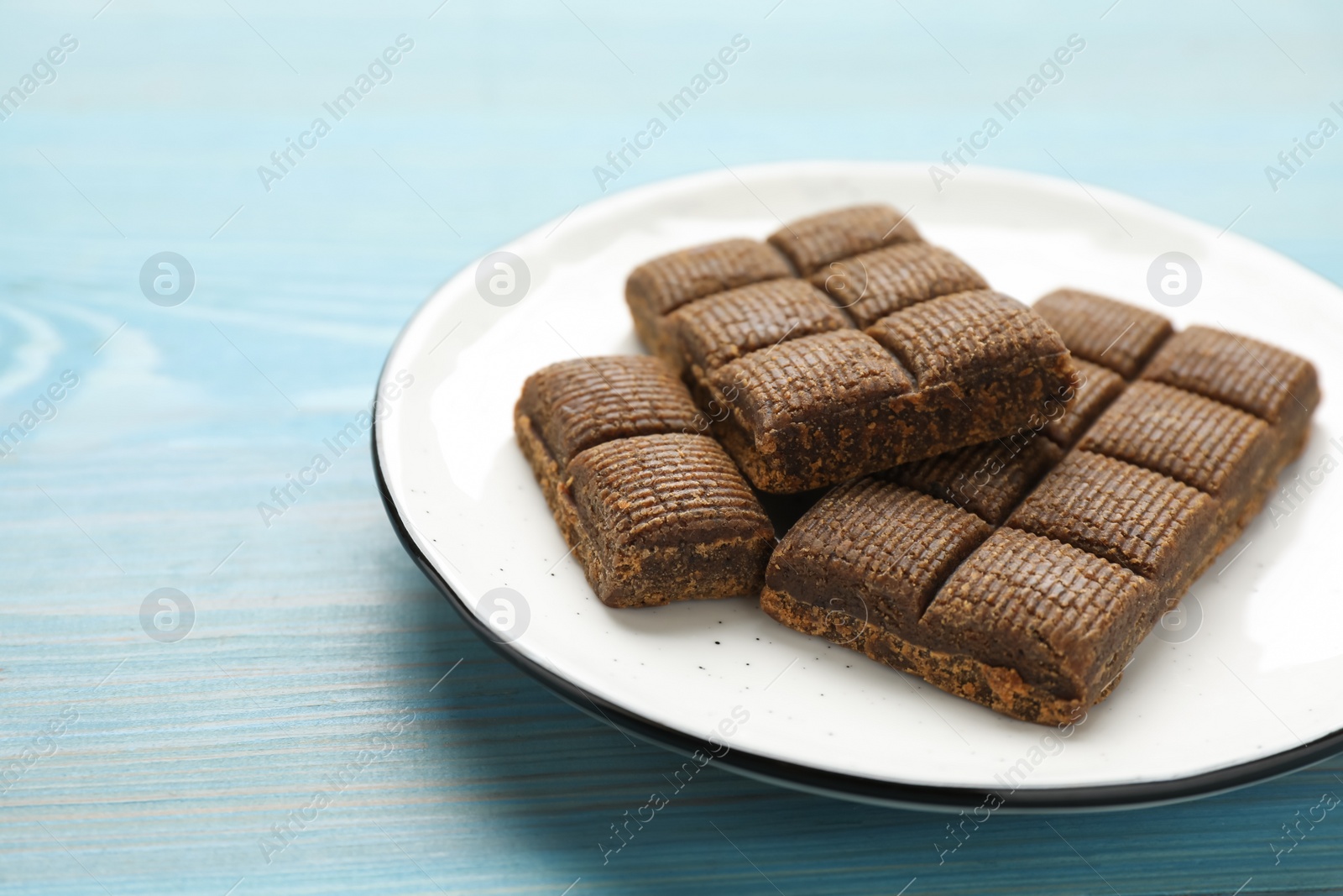 Photo of White plate with delicious and healthy hematogen on blue wooden table, closeup