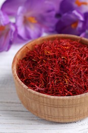 Photo of Dried saffron and crocus flowers on white wooden table, closeup