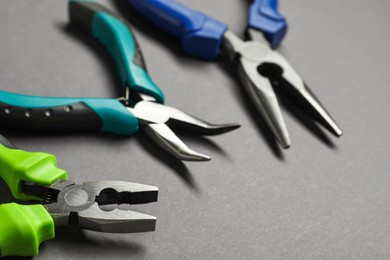 Photo of Different pliers on grey background, closeup view