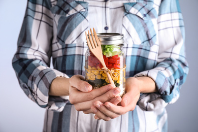 Photo of Woman holding glass jar with healthy meal, closeup