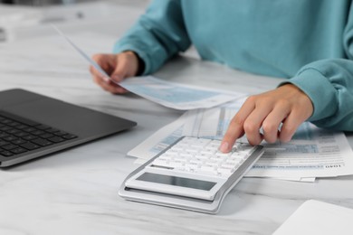 Photo of Woman calculating taxes at white table, closeup