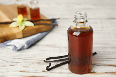 Aromatic homemade vanilla extract on white wooden table. Space for text