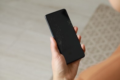 Photo of Woman holding damaged smartphone indoors, closeup. Device repairing