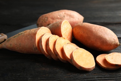 Photo of Fresh ripe sweet potatoes on wooden background