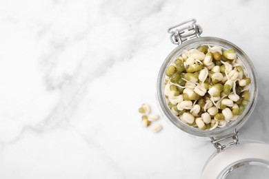 Glass jar with sprouted green mung beans on white marble table, top view. Space for text