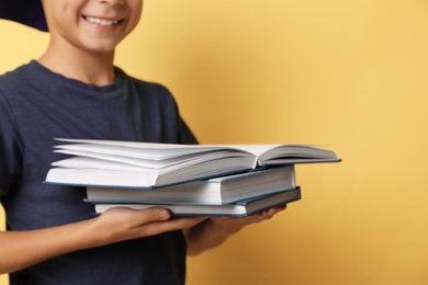 Photo of Little boy reading book on yellow background, closeup