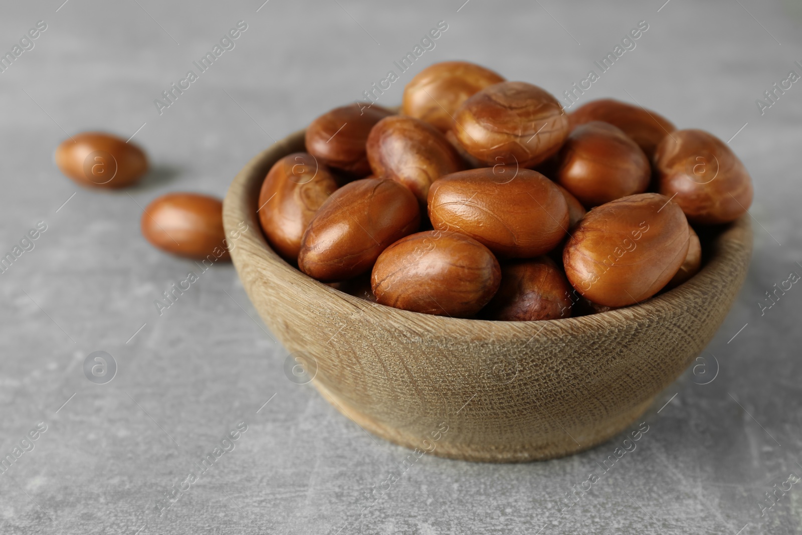 Photo of Wooden bowl with jackfruit seeds on light grey table, closeup