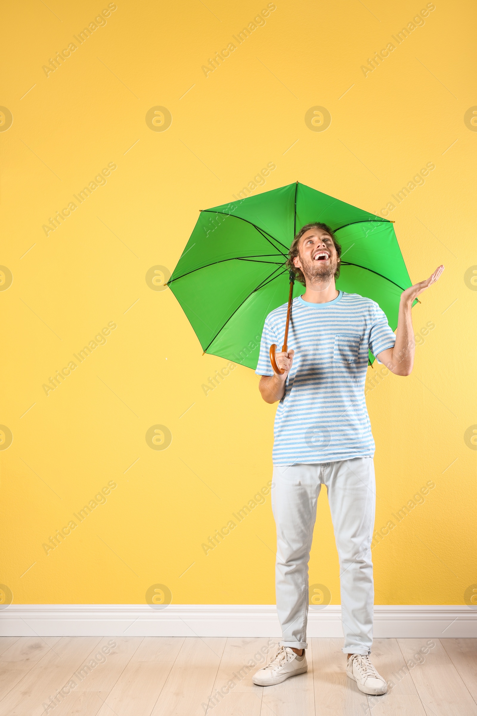 Photo of Man with green umbrella near color wall